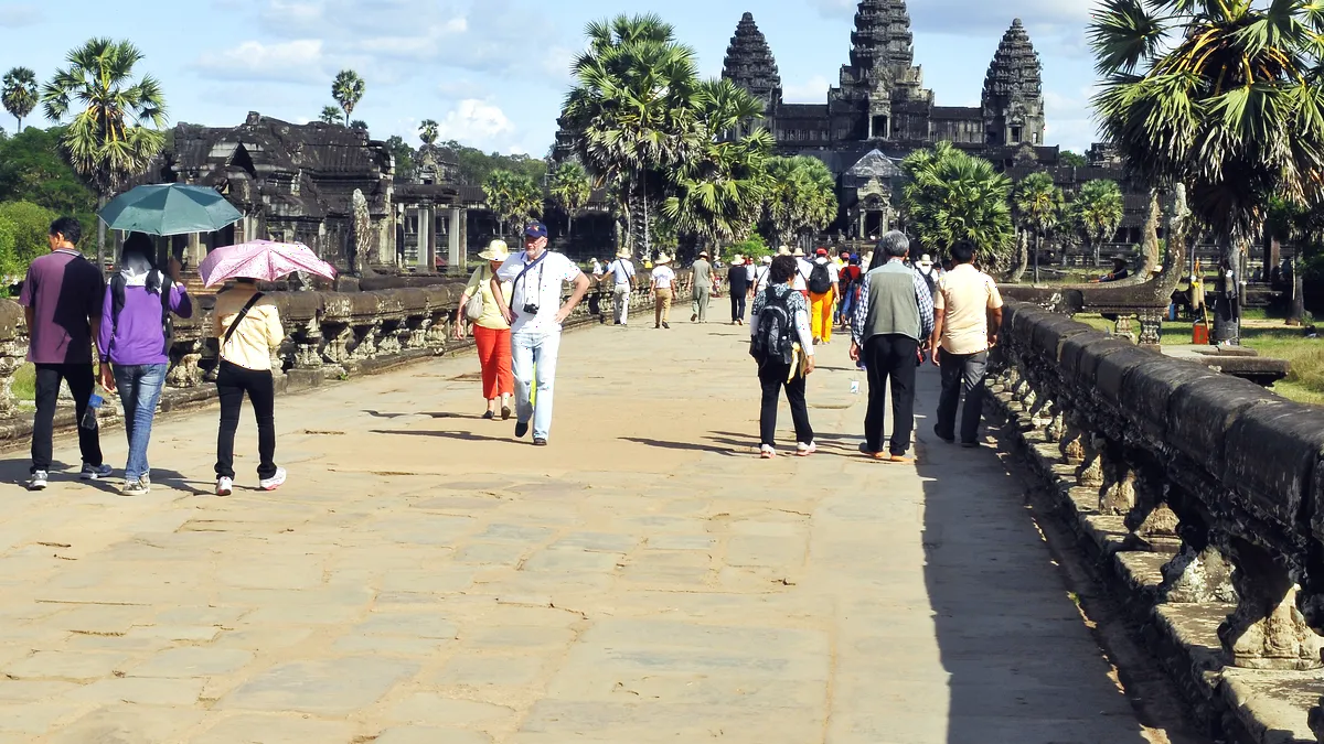 Visitors walking along the Angkor Wat causeway toward the main temple