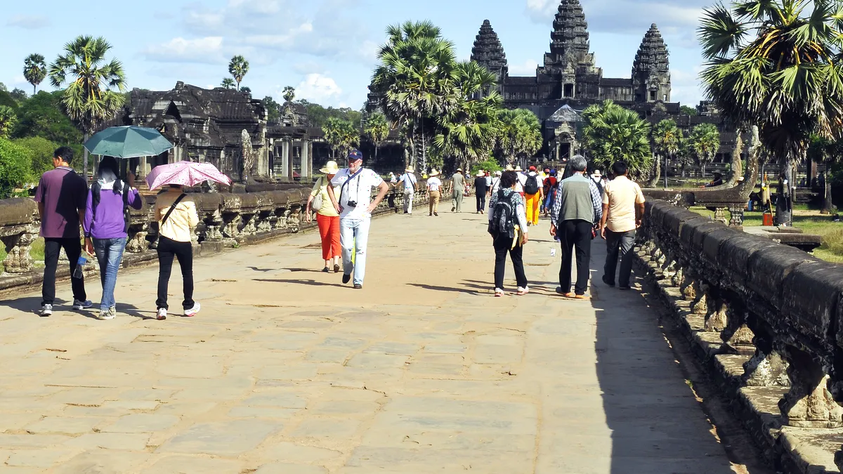 Visitors walking along the Angkor Wat causeway toward the temple entrance