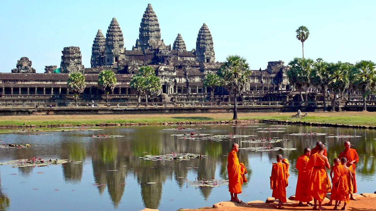 Buddhist monks walking beside the reflection pond in front of Angkor Wat